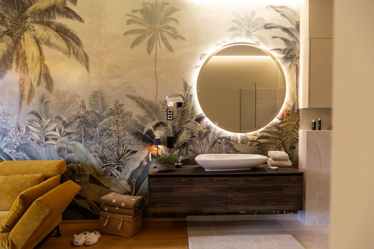 Badezimmer mit Dschungeltapete und rundem Leuchtspiegel