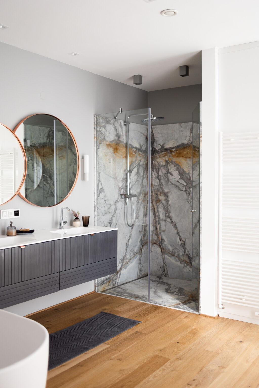 Badezimmer mit rundem Spiegel und Natursteindusche